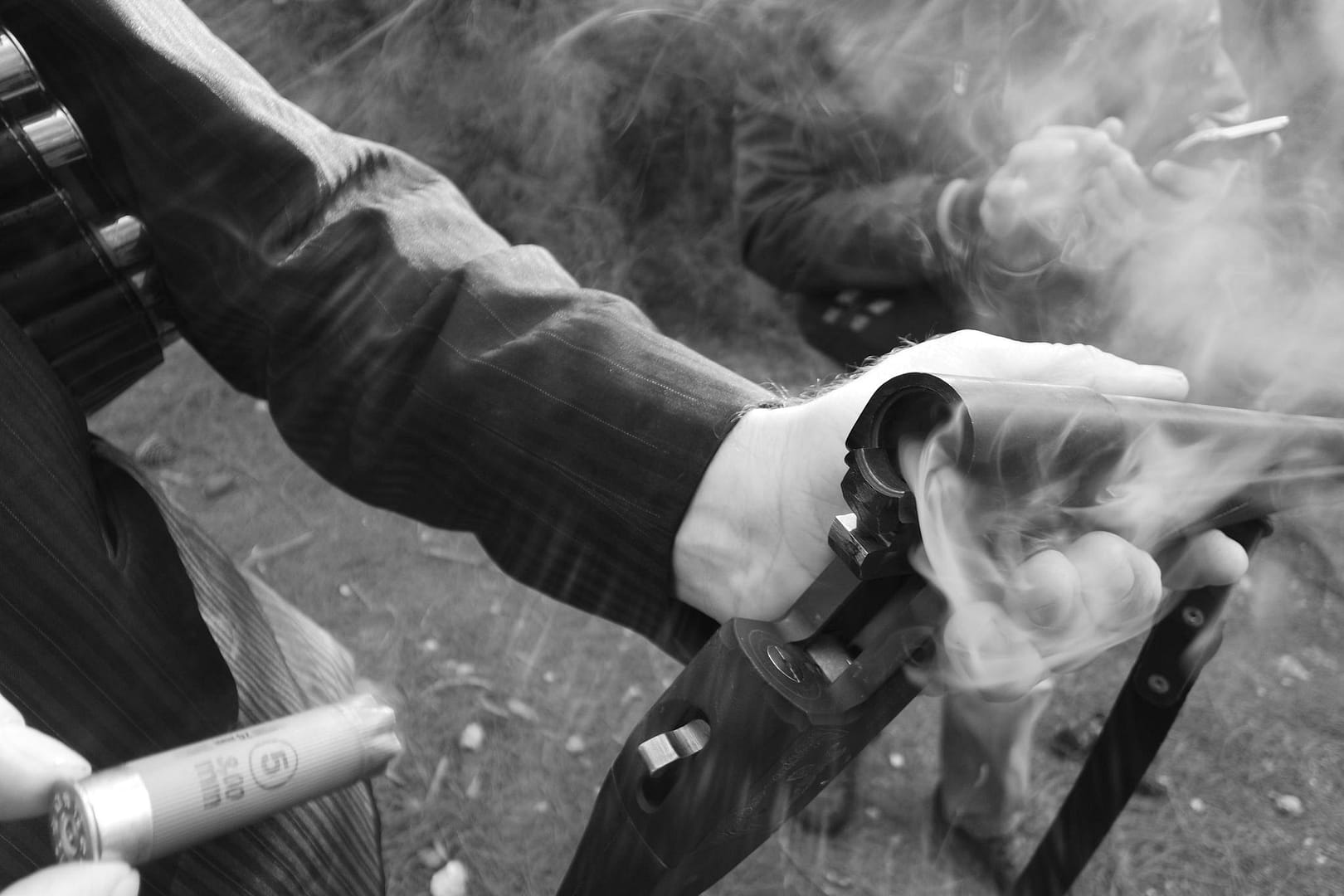 Detailed shot of a hand holding a smoking shotgun, highlighting the action and movement.